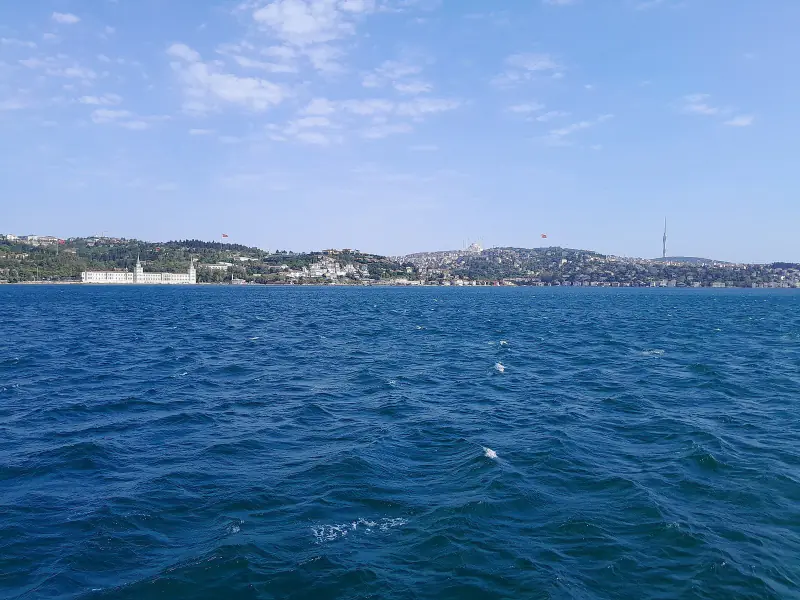 Calm blue water of the Bosphorus on a clear morning, with the far shore on the horizon