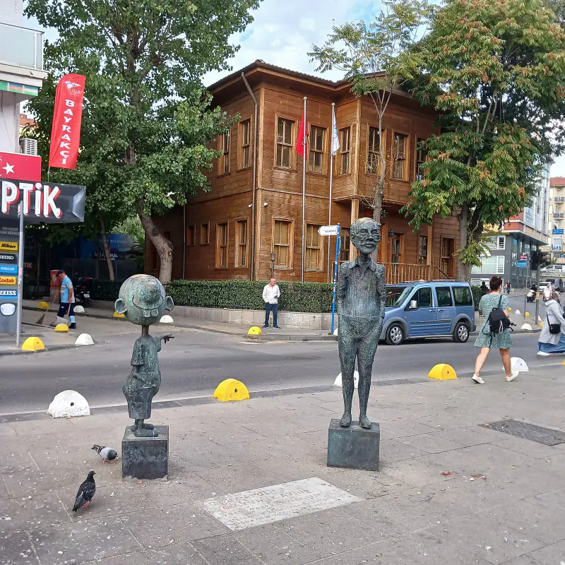 A tree-lined street in Kadıköy, Istanbul, with bronze statues on the pavement